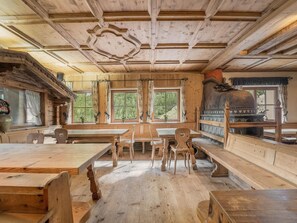 A rustic wooden interior with a large wooden table and benches, a fireplace, and large windows. - Quaint Alpine Hut In The Stubaital With Sauna (Neustift Im Stubaital)