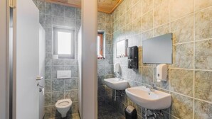 A bathroom with a toilet, two sinks, a mirror, and a window.