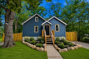 Une maison à deux étages avec un porche à l’avant, une clôture en bois et une pelouse bien entretenue.