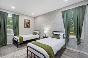 Une chambre avec deux lits simples, une table de chevet avec une lampe et un papier peint à motifs.