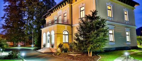 A two-story building with a symmetrical facade, large windows, and a central entrance with steps.