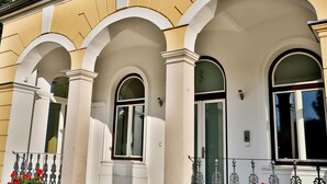 Fachada de edificio con tres ventanas arqueadas y un balcón con barandilla de metal.