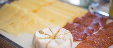 Una tabla de quesos con distintos tipos de queso y embutidos curados.