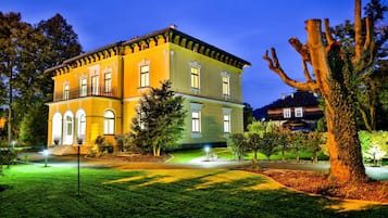 Un edificio de dos pisos con fachada simétrica, ventanas arqueadas y un balcón en el nivel superior.