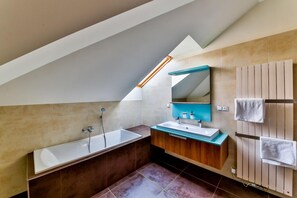 A modern bathroom with a freestanding bathtub, a vanity with a mirror, and a towel rack.