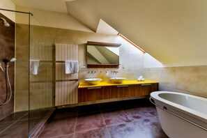 A modern bathroom with a glass shower enclosure, a freestanding bathtub, and a vanity with two sinks.