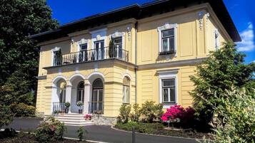 A two-story building with a symmetrical facade, arched windows, and a balcony with railings.