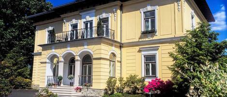A two-story building with a symmetrical facade, arched windows, and a balcony with railings.