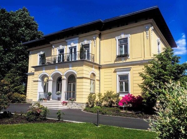 A two-story building with a symmetrical facade, arched windows, and a balcony with railings.