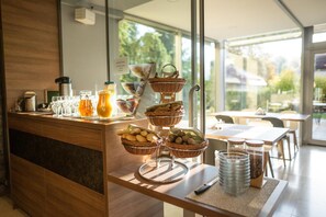A breakfast buffet with wicker baskets, a coffee station, and a view of the outdoors. - Villa Aurelie (Velke Losiny)