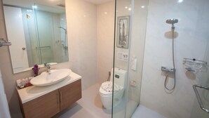 Uma casa de banho moderna com cabine de duche em vidro, lavatório com bancada e sanita.