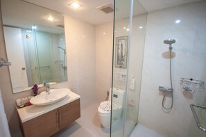 Un baño moderno con cabina de ducha de vidrio, un lavabo con tocador y un inodoro.