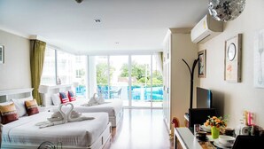 Quarto de hotel com duas camas, área de refeições e varanda com vista.