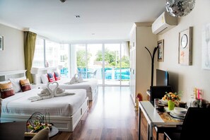 Una habitación de hotel con dos camas, zona de comedor y balcón con vistas.