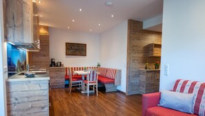Una cocina moderna con armarios de madera, un comedor con banco y una sala de estar con sofá.