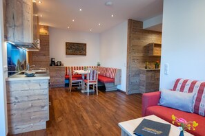 Une cuisine moderne avec des meubles en bois, un coin repas avec un banc et un salon doté d’un canapé.