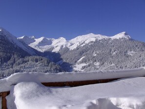 Un paysage de montagne enneigé, avec une structure en bois au premier plan.