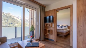 Una habitación de hotel con un ventanal grande, un escritorio con un florero, una cama con almohadas y un televisor montado en la pared.