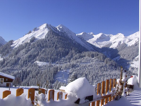 Un paysage de montagne avec des pentes enneigées et un bâtiment doté d’un toit en pente.