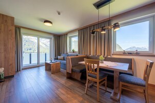 A modern interior with a dining area, seating, and large windows offering a mountain view.