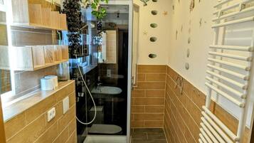 Un baño con ducha, dos lavamanos, un inodoro y un perchero para toallas.
