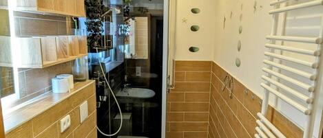 Un baño con ducha, dos lavamanos, un inodoro y un perchero para toallas.