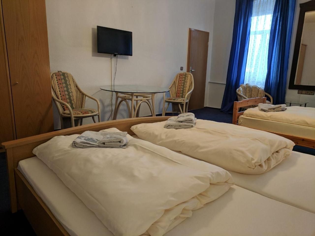 Una habitación de hotel con dos camas, televisión, una mesa y dos sillas.