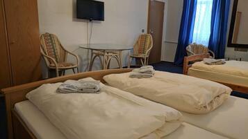Una habitación de hotel con dos camas, televisión, una mesa y dos sillas.
