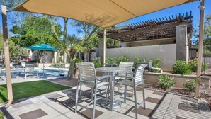 Un área de patio exterior con piscina, pérgola y zona de estar.