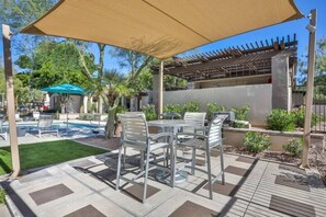 Uma área de estar externa com piscina, pérgola e espaço para sentar.