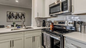 Una cocina moderna con electrodomésticos de acero inoxidable, armarios blancos y un elemento decorativo en la pared.