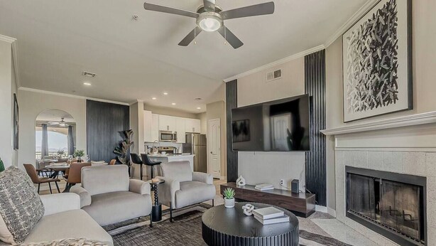 Una sala moderna con chimenea, televisor y un comedor visible al fondo.