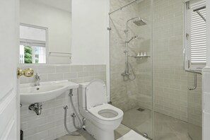 A bathroom with a white sink, toilet, and shower. - Aadya Tea Bangalows By Aahaasa (Upcot)