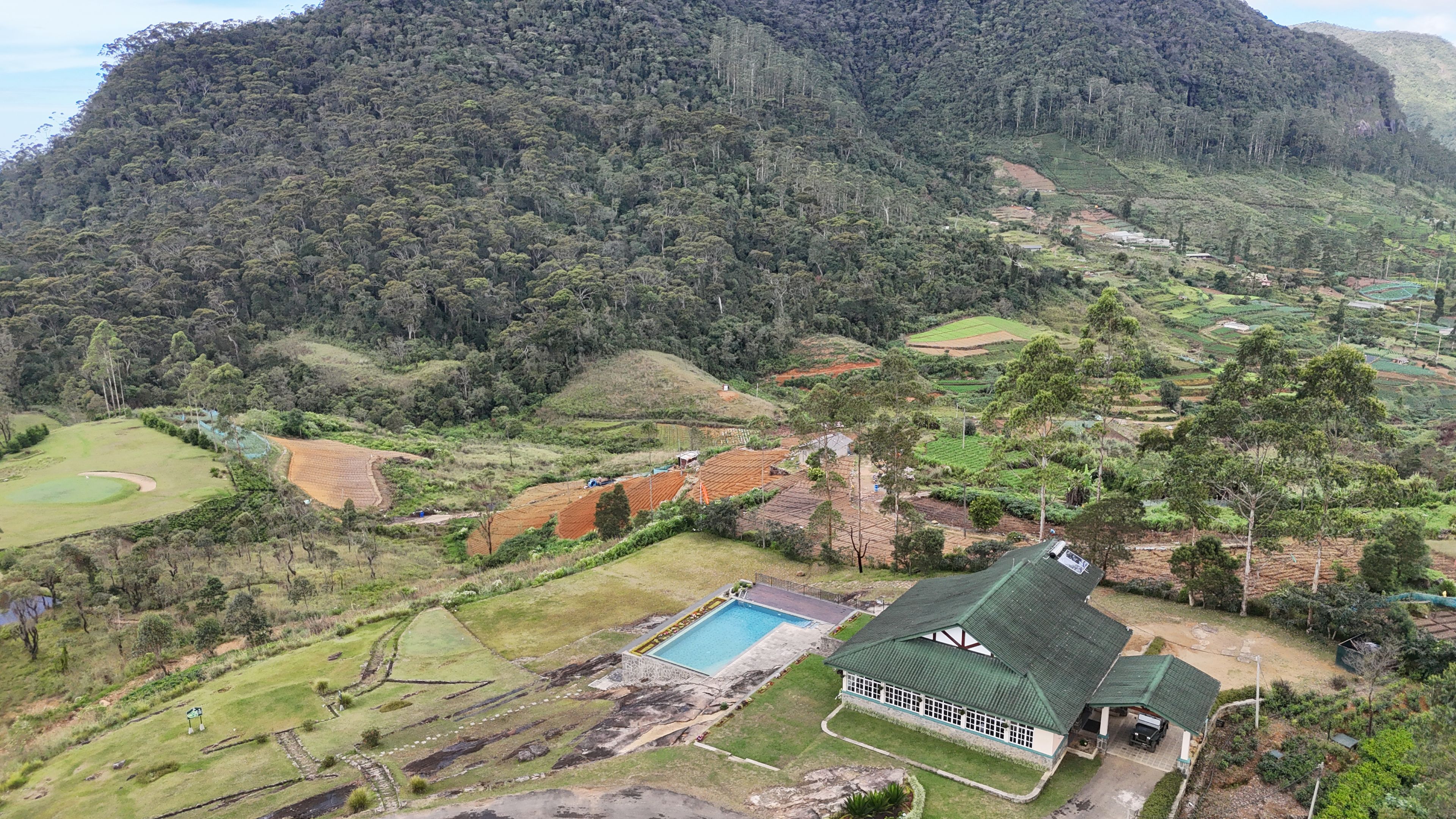 Une propriété dotée d’une piscine, d’un court de tennis et offrant une vue sur une montagne boisée.