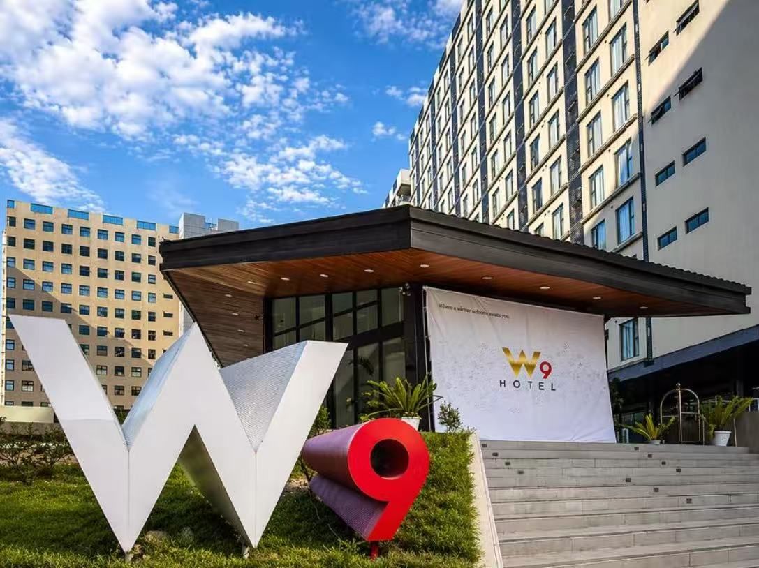 A hotel entrance with a large 'W9' sign, a modern building facade, and a clear sky.