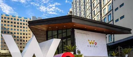 A hotel entrance with a large 'W9' sign, a modern building facade, and a clear sky.