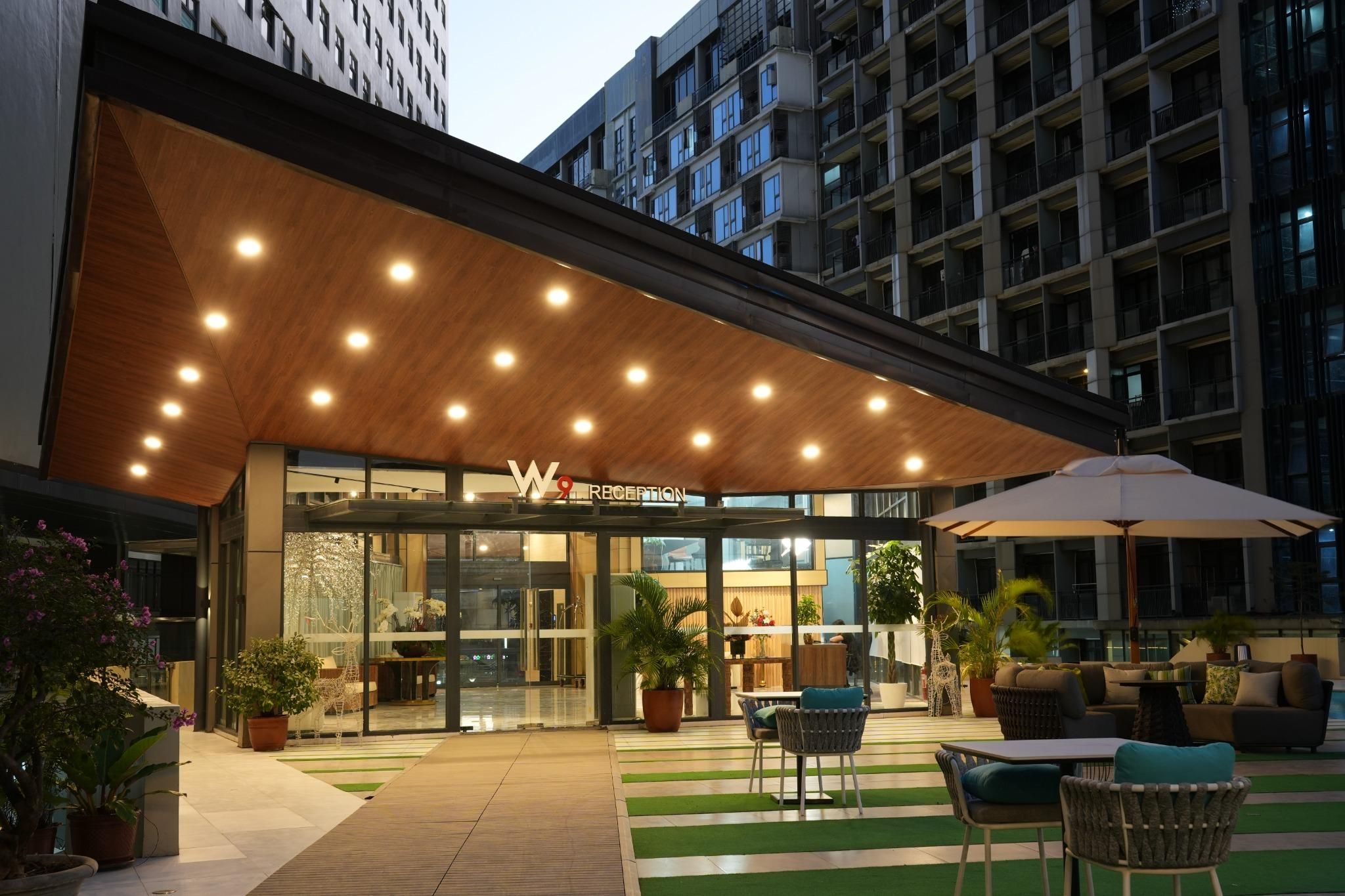 A hotel reception with a modern design, featuring a wooden ceiling and a glass entrance.