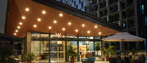 A hotel reception with a modern design, featuring a wooden ceiling and a glass entrance.