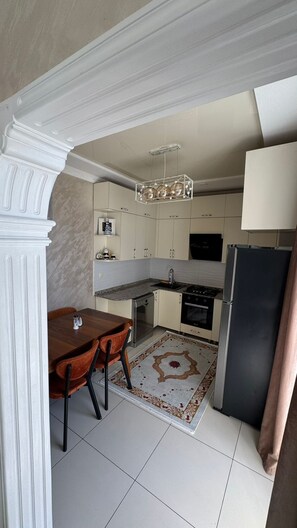 A modern kitchen with a dining area, featuring a marble countertop, stainless steel appliances, and a decorative rug. - Umid 2026 Hotel (Batumi)