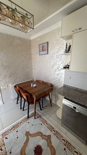 A modern kitchen with a dining table, chairs, a built-in oven, and a countertop. - Umid 2026 Hotel (Batumi)
