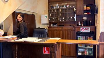 A reception desk with a 'No Smoking' sign, a clock, and a 'Call Emergency' sign.