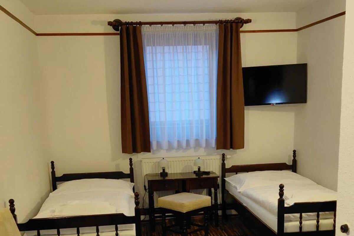A room with three wooden beds, a desk, and a chair.