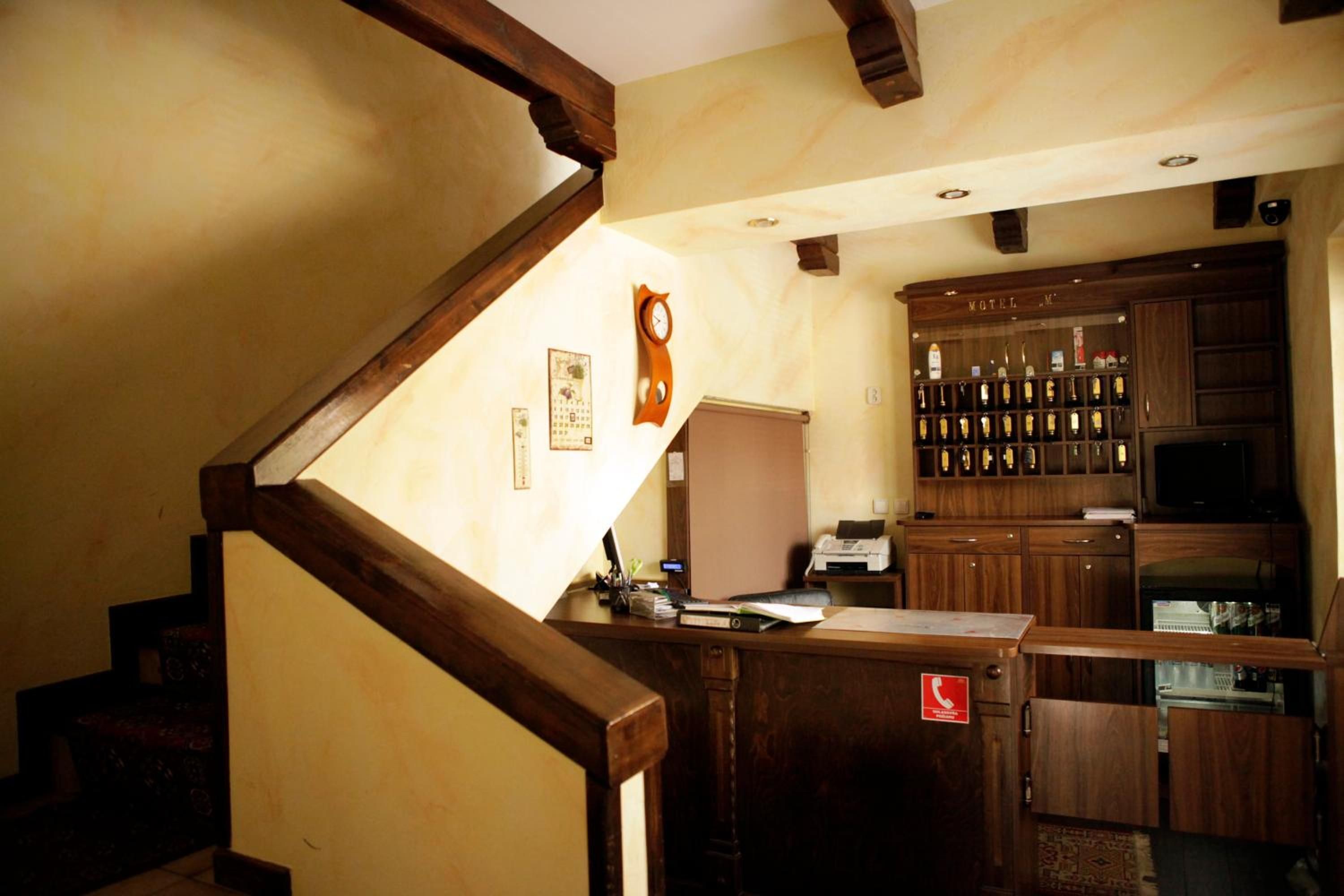 Zona de bar de un hotel con mobiliario de madera, un reloj y una vitrina de licores.