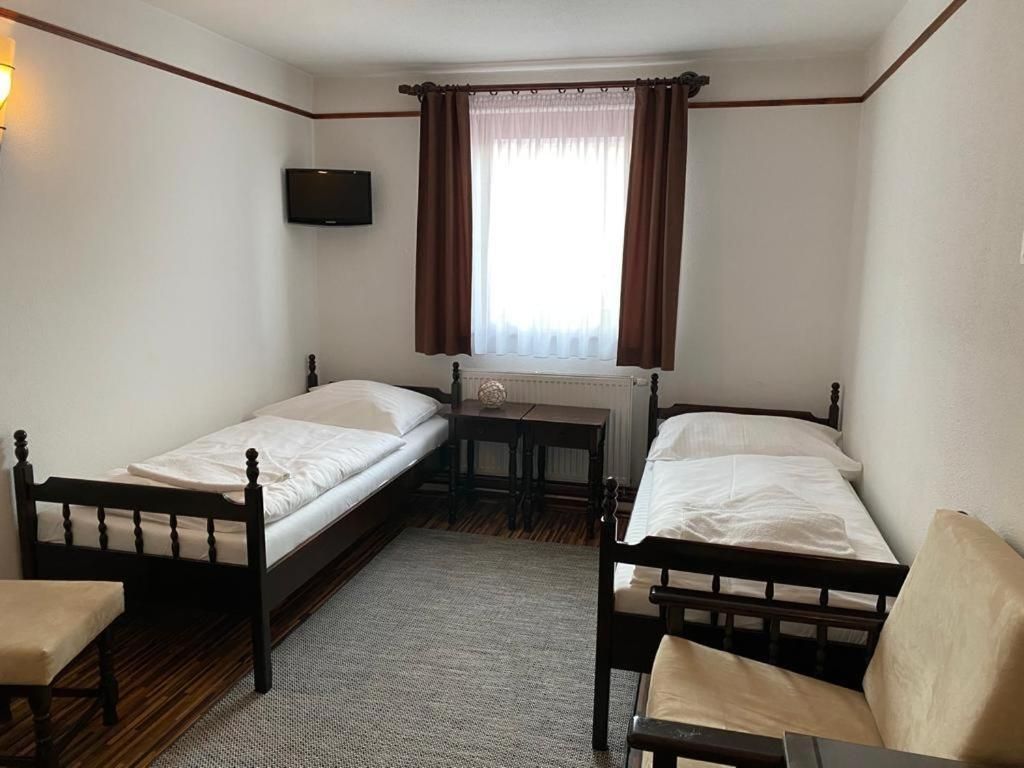 Una habitación con dos camas individuales, una mesita, una silla y un televisor montado en la pared.