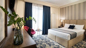 A hotel room with a bed, bedside table, lamp, chair, and a plant.