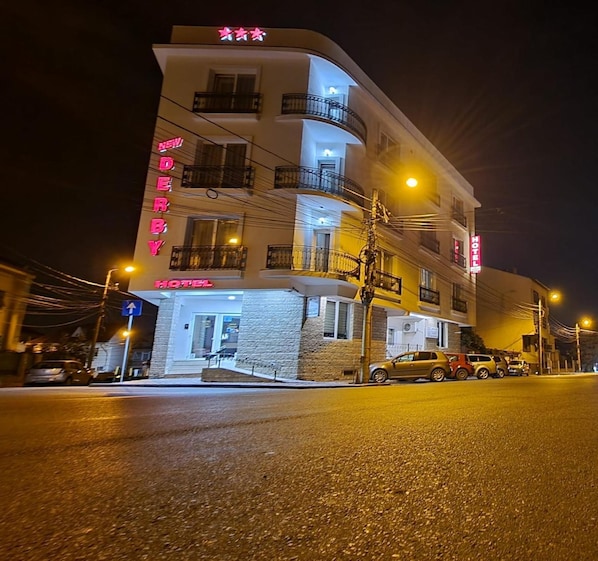 A multi-story hotel with a neon sign, balconies, and a visible entrance.