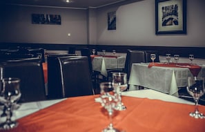 A restaurant interior with tables set for dining, chairs, and wine glasses.