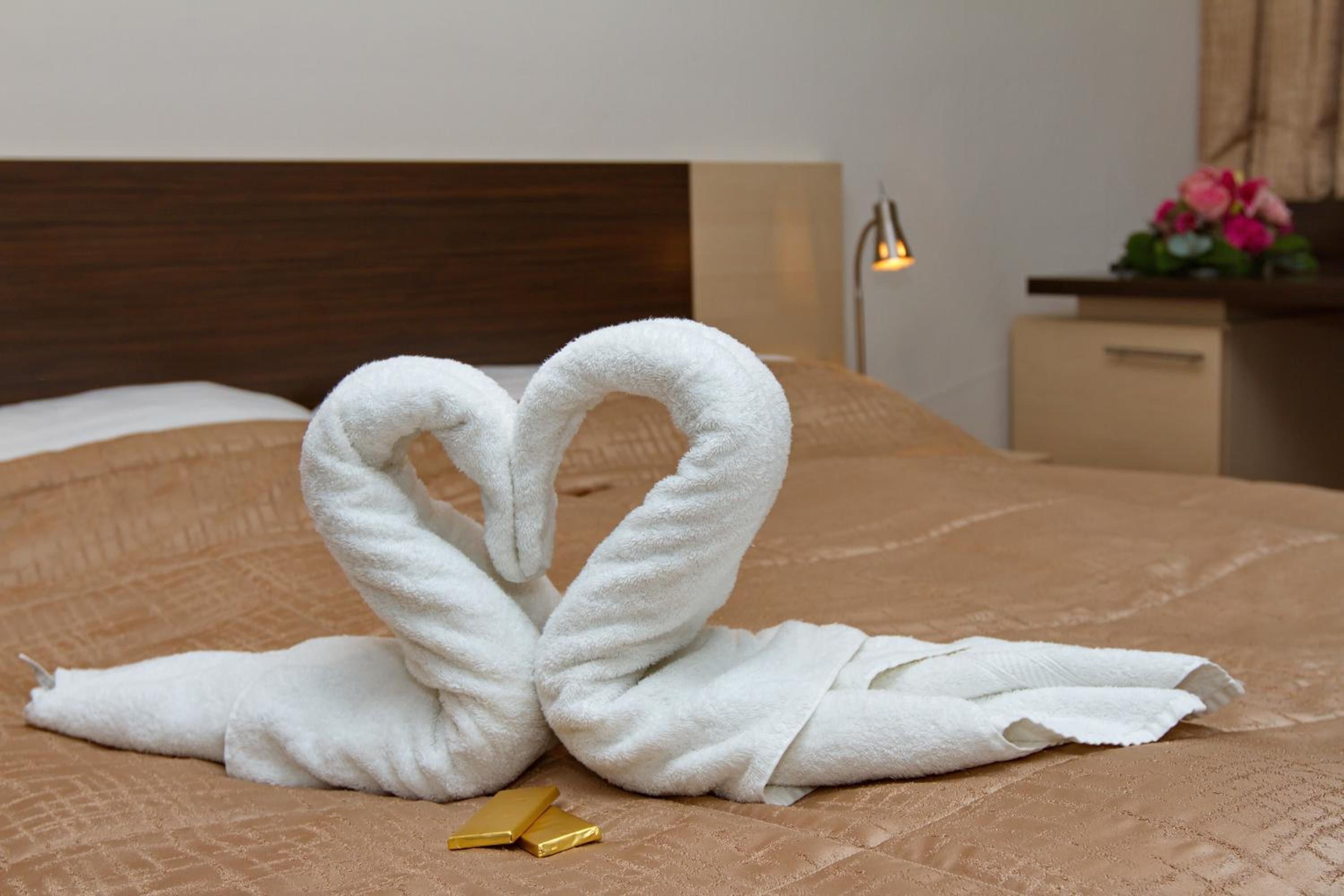 Ein Bett mit einer braunen Steude, einem Herz aus weißen Handtüchern und einem goldenen Gegenstand.