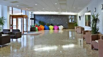 A spacious lobby with seating areas, a reception desk, and a wall with clocks.