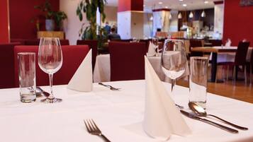 A restaurant setting with tables set for dining, including wine glasses, cutlery, and napkins.